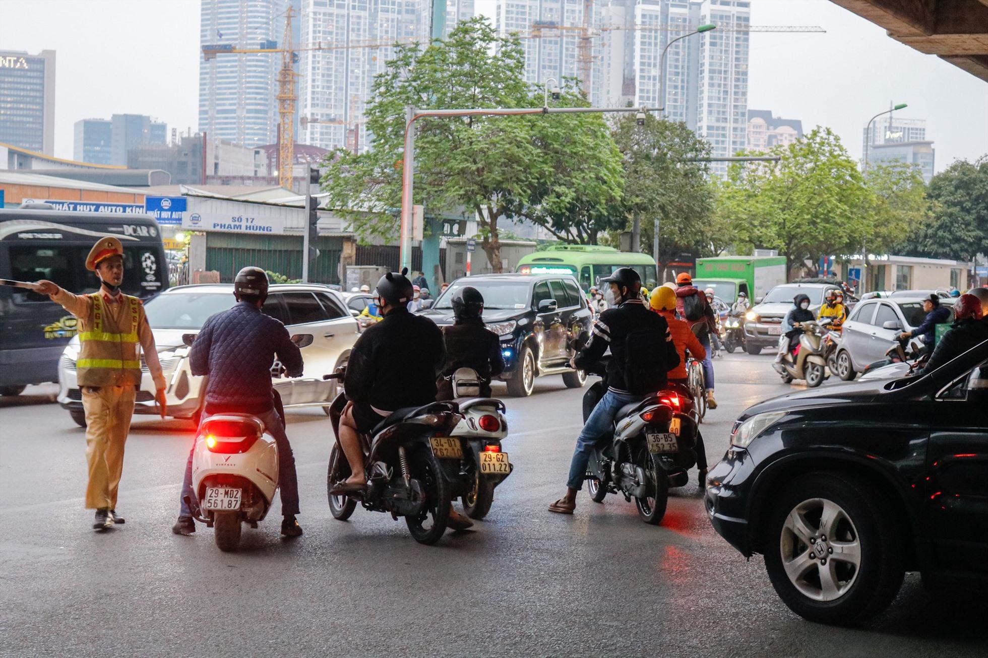 Cảnh sát giao thôn nhắc nhở phương tiện có ý định rẽ trái tại nút giao sang đường Tôn Thất Thuyết. Ảnh: Thu Hiền