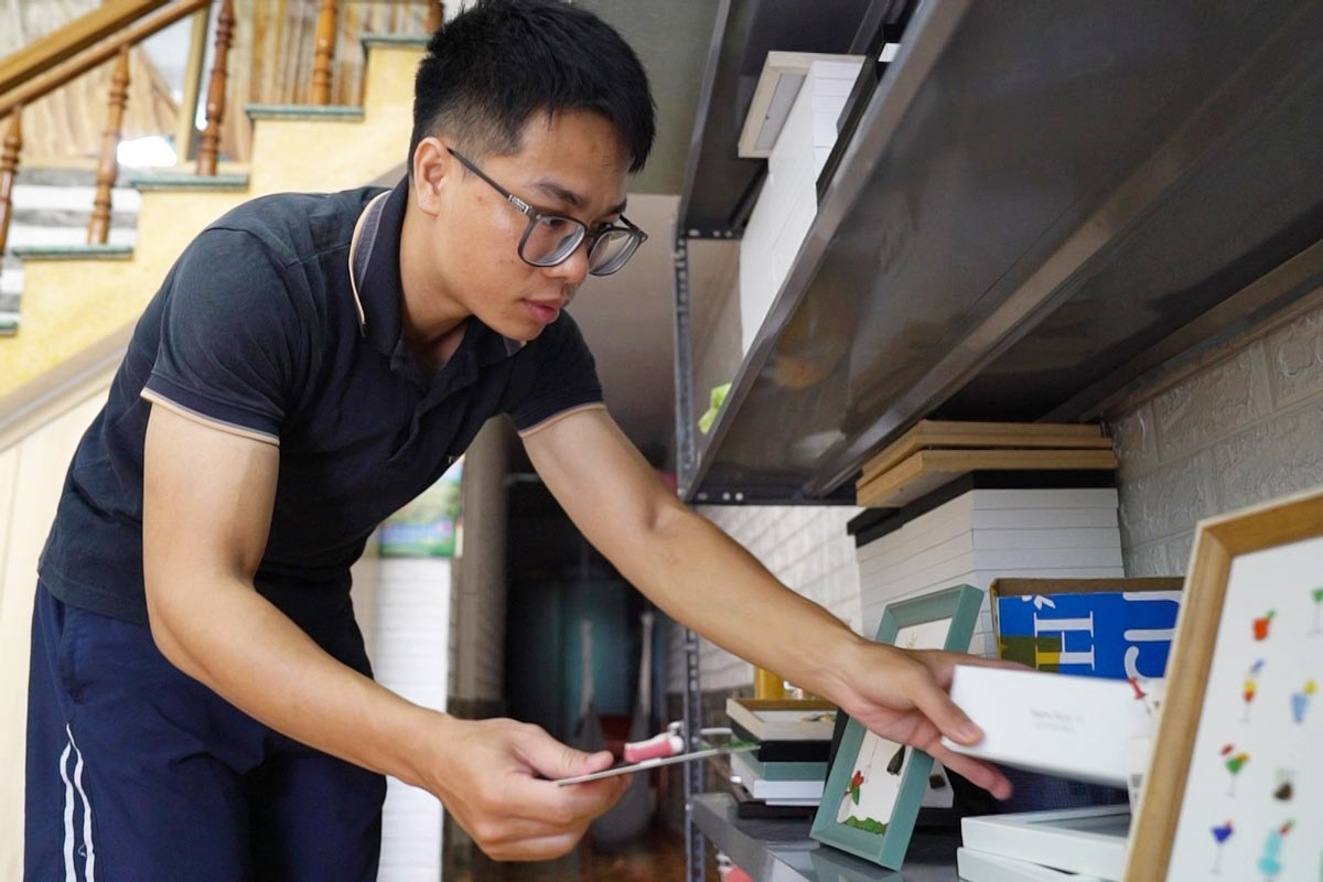 Anh Hứa Duy Thanh đang sắp xếp các bức tranh làm từ thủy tinh vỡ. Ảnh: Đoàn Hưng