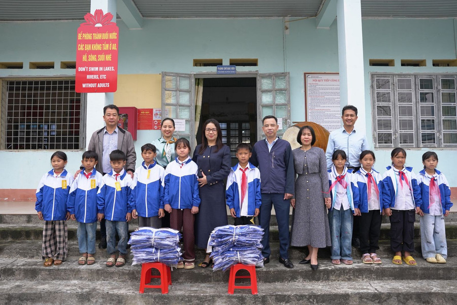 Ông Nguyễn Minh Hiệu (hàng đầu, thứ 6 tính từ bên phải) trao tặng áo ấm và chụp ảnh lưu niệm cùng cô trò nhà trường.
